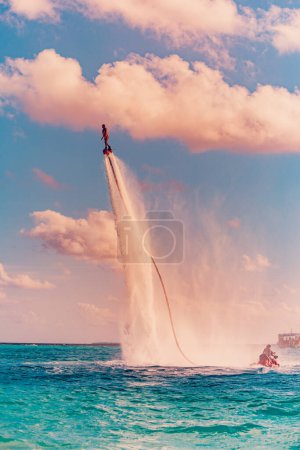 Photo for Island sunset. Professional fly board rider doing back flip with tropical resort island background. Sunset sport and summer activity background, fun water sport - Royalty Free Image