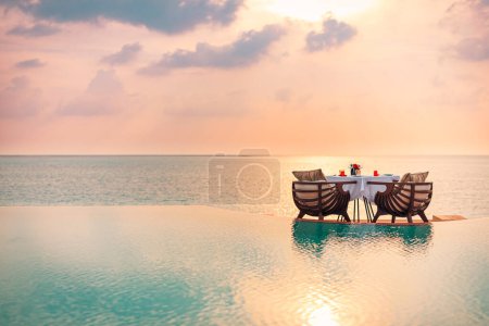 Meerblick unter Sonnenuntergang mit Esstisch und Infinity-Pool. Romantisch beschaulicher Kurzurlaub zu zweit, Paarkonzept. Stühle, Essen und Romantik. Luxus-Destination Essen, Flitterwochen Vorlage