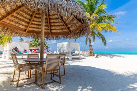 Téléchargez les photos : Table et chaises sous le parapluie sur la plage tropicale - en image libre de droit