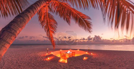 Foto de Increíble cena romántica en la playa en la arena con velas bajo el cielo del atardecer. Romance y amor, cena de destino de lujo, configuración de mesa exótica con vista al mar. - Imagen libre de derechos