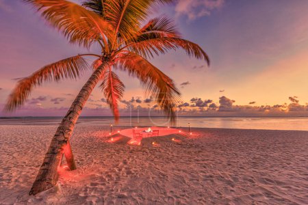 Téléchargez les photos : Incroyable dîner romantique sur la plage de sable avec des bougies sous le soleil couchant. Romance et amour, destination de luxe, installation de table exotique avec vue sur la mer. - en image libre de droit