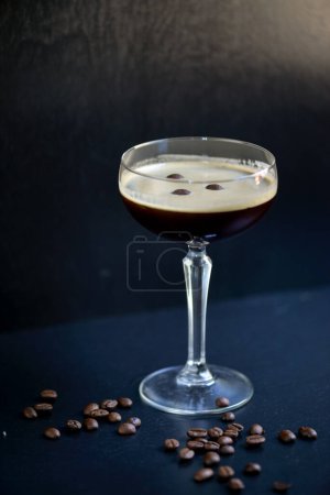 Foto de Cóctel alcohólico de café en un vaso sobre un fondo oscuro con granos de café espolvoreados - Imagen libre de derechos