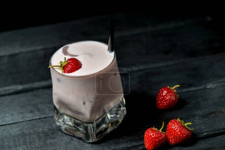 Téléchargez les photos : Cocktail de fraises au lait dans un verre aux fraises sur fond noir avec décor - en image libre de droit