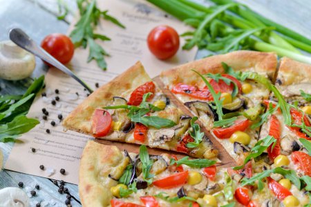 Téléchargez les photos : Pizza végétarienne aux tomates, champignons et herbes tranchées sur une planche avec des ingrédients sur la table - en image libre de droit