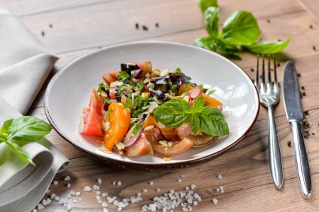 Téléchargez les photos : Salade géorgienne au basilic tamatami et amandes dans une belle assiette d'argile sur la table - en image libre de droit