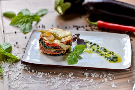 Photo for Georgian eggplant dish with tomatoes garnished with hot green pepper on a white plate close-up - Royalty Free Image