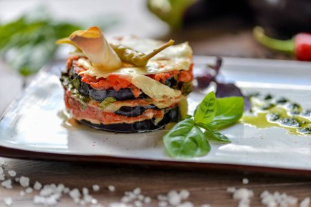 Téléchargez les photos : Plat d'aubergines géorgiennes aux tomates garni de piment vert chaud sur une assiette blanche close-up - en image libre de droit