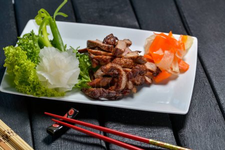 Téléchargez les photos : Porc frit, cuisine chinoise avec baguettes et légumes - en image libre de droit