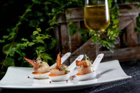 Foto de Camarones y salsa en cucharas y vino blanco sobre fondo - Imagen libre de derechos