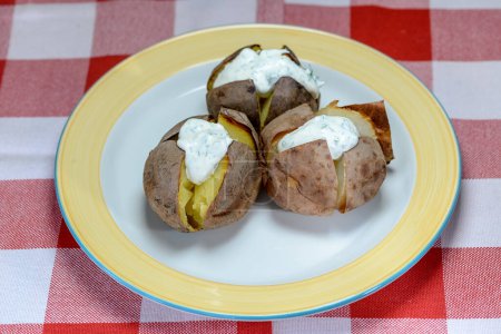 Foto de Patatas hervidas con crema agria y cebollas verdes en el plato. - Imagen libre de derechos