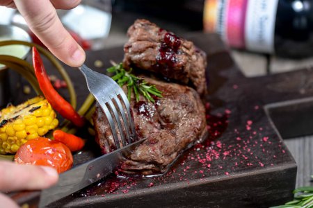 Photo for Hands with grilled steak and  vegetables on wooden board - Royalty Free Image