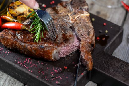 Photo for Hand and grilled steak with vegetables on wooden board - Royalty Free Image