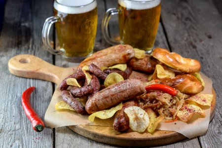 Téléchargez les photos : Tasses à bière avec bretzels, bratwurst, choucroute et poivrons sur table en bois - en image libre de droit