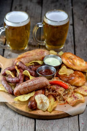 Téléchargez les photos : Tasses à bière avec bretzels, bratwurst, choucroute et poivre sur table en bois - en image libre de droit