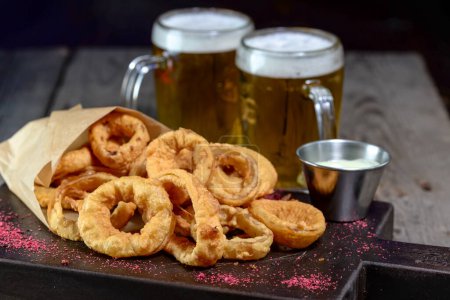 Foto de Tazas de cerveza con anillos de calamar en una tabla de madera - Imagen libre de derechos