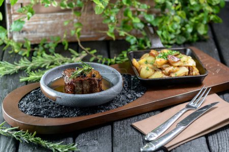 Photo for Delicious beef steak with potatoes and herbs served on table, closeup - Royalty Free Image