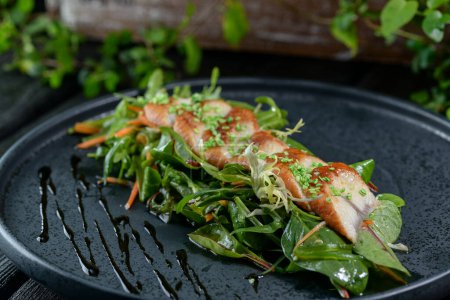 Téléchargez les photos : Savoureux poisson grillé et salade sur assiette noire - en image libre de droit