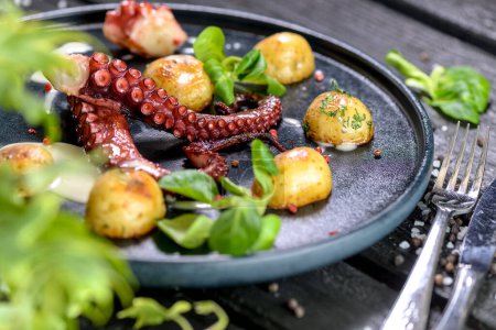 Foto de Tentáculos de pulpo grandes en un plato con verduras y hierbas a la parrilla - Imagen libre de derechos