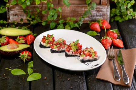 Photo for Bruschetta with fresh strawberries and avocado  on plate, close - up. - Royalty Free Image
