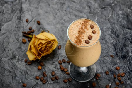 Foto de Bebida de café en un vaso decorado con granos de café en una mesa con una rosa - Imagen libre de derechos