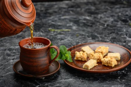 Téléchargez les photos : Petit déjeuner oriental en faïence sur la table avec du thé versé dans une tasse - en image libre de droit