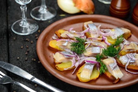 Foto de Filete de arenque en patatas con cebolla en un plato - Imagen libre de derechos