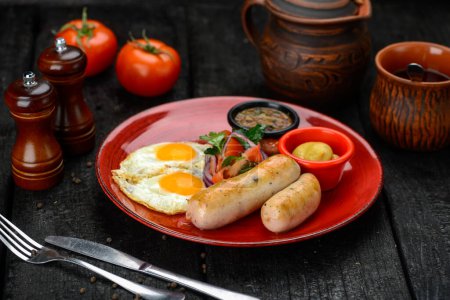 Téléchargez les photos : Petit déjeuner oeuf frit avec saucisses et légumes dans une assiette rouge - en image libre de droit