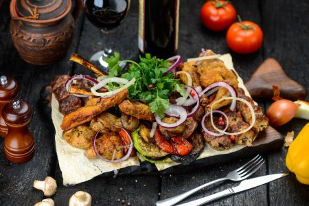 Téléchargez les photos : Viande grillée aux légumes et vin rouge sur une planche de bois sur fond noir - en image libre de droit