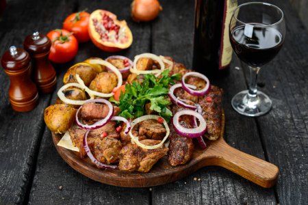 Téléchargez les photos : Viande grillée aux légumes sur une planche de bois sur fond noir - en image libre de droit