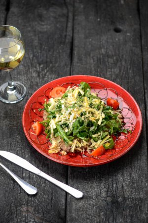 Téléchargez les photos : Salade géorgienne avec roquette, fromage et viande dans une assiette avec vin - en image libre de droit