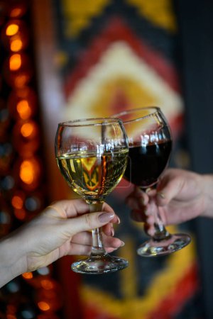 Photo for Two glasses with white wine and red wine in the hands - Royalty Free Image