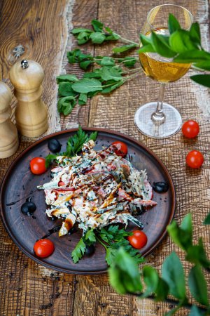 Téléchargez les photos : Salade de légumes géorgienne dans une assiette en argile sur fond de bois avec tomates et légumes verts - en image libre de droit