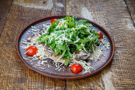 Téléchargez les photos : Salade géorgienne à la roquette, fromage et viande dans une assiette aux graines de grenade - en image libre de droit