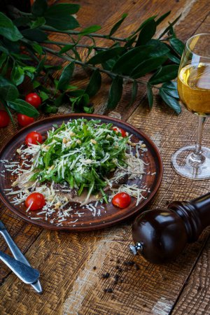 Téléchargez les photos : Salade géorgienne à la roquette, fromage et viande dans une assiette aux graines de grenade - en image libre de droit