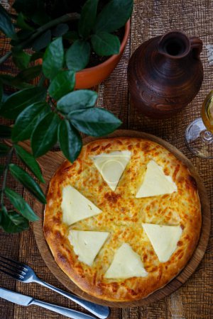 Téléchargez les photos : Pain plat géorgien au fromage sur planche de bois sur table avec vin - en image libre de droit