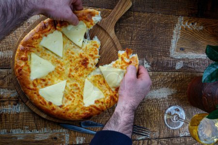 Téléchargez les photos : Pain plat géorgien au fromage sur plateau en bois sur table avec vin et mains masculines - en image libre de droit