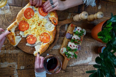 Photo for Georgian flatbread with tomatoes on a wooden table with an eggplant snack and a jug of wine - Royalty Free Image