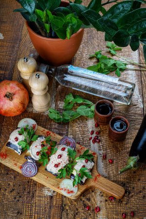 Téléchargez les photos : Apéritif géorgien d'aubergine en rouleaux avec remplissage saupoudré de graines de grenade sur la table avec chacha et plante - en image libre de droit