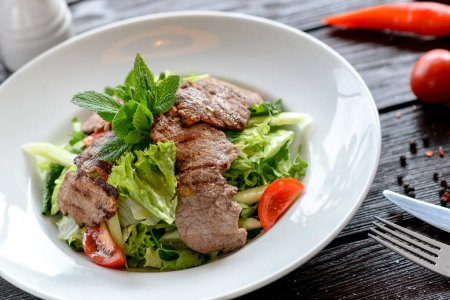 Foto de Sabrosa ensalada con carne y verduras en el plato - Imagen libre de derechos