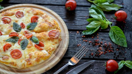 Foto de Pizza con tomates y albahaca en una tabla de madera - Imagen libre de derechos