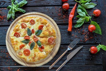 Foto de Pizza con tomates y albahaca en una tabla de madera - Imagen libre de derechos