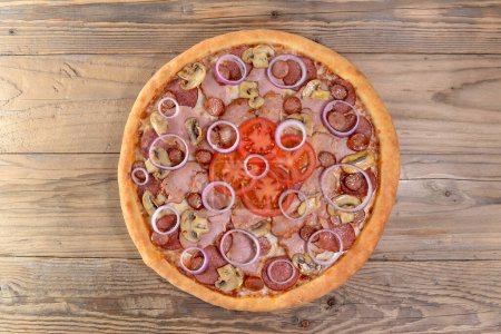 Foto de Pizza de pepperoni picante con salami, cebolla, tomates en el fondo, de cerca - Imagen libre de derechos