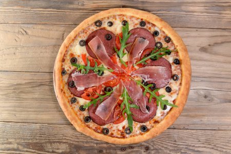 Foto de Deliciosa pizza con tomates, carne, rúcula y aceitunas - Imagen libre de derechos