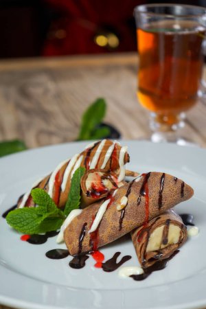 Foto de Tortitas sabrosas con chocolate y plátano y té en vidrio - Imagen libre de derechos