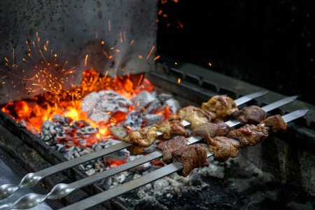 Foto de Kebabs de carne en pinchos se asan a la parrilla sobre carbones - Imagen libre de derechos