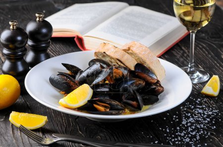 Photo for Boiled mussels in a plate with lemon and bruschetta with book - Royalty Free Image