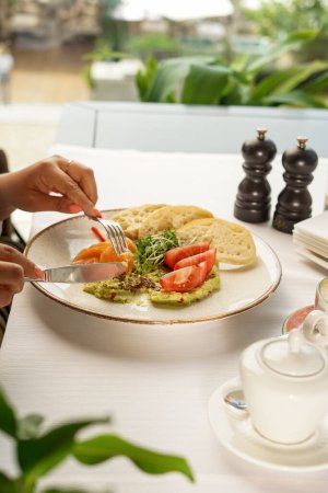 Photo for Female hands with salmon, avocado, toast and coffee - Royalty Free Image