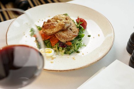 Foto de Primer plano - vista de la deliciosa carne con ensalada y vino tinto en la mesa - Imagen libre de derechos