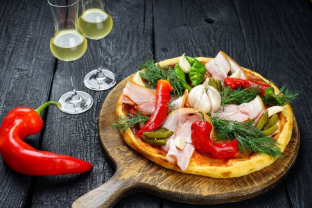 Téléchargez les photos : Pizza au jambon, concombres marinés, ail, poivrons rouges et fromage sur une table en bois. - en image libre de droit