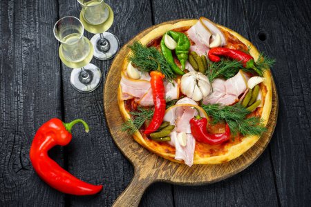 Photo for Pizza with ham, pickled cucumbers, garlic , red peppers and cheese on a wooden table. - Royalty Free Image
